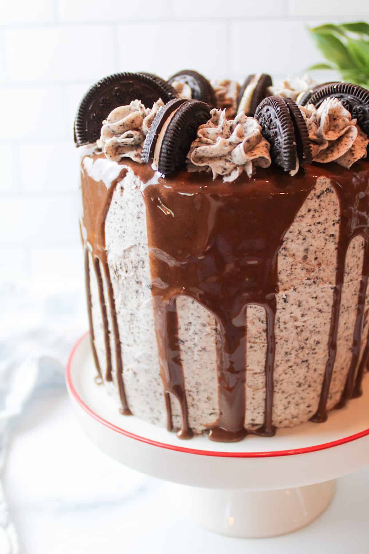 chocolate drip cake with oreo buttercream frosting garnished with halved oreo cookies.