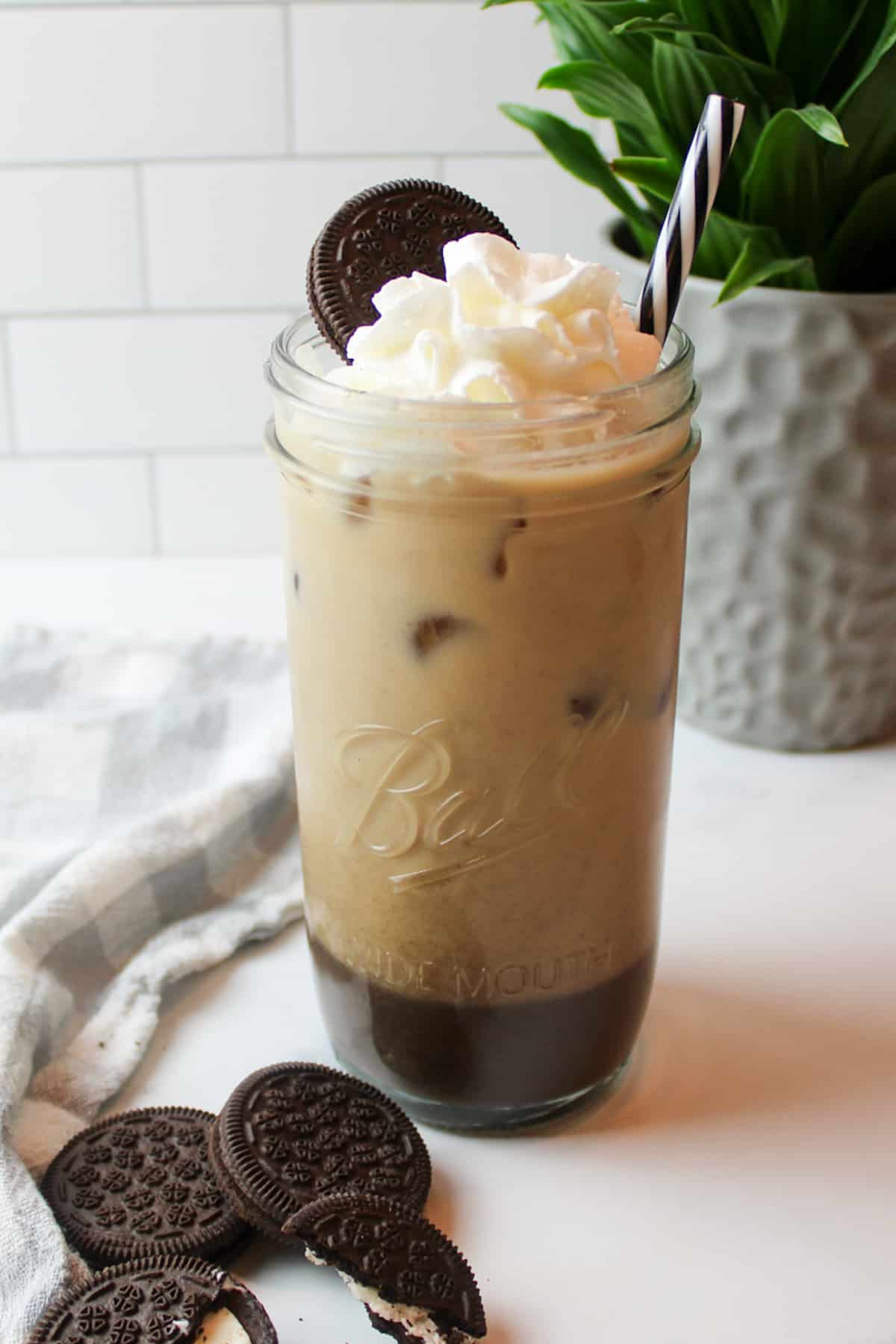 a tall glass cup full of iced oreo coffee and garnished with whipped cream and a cookie