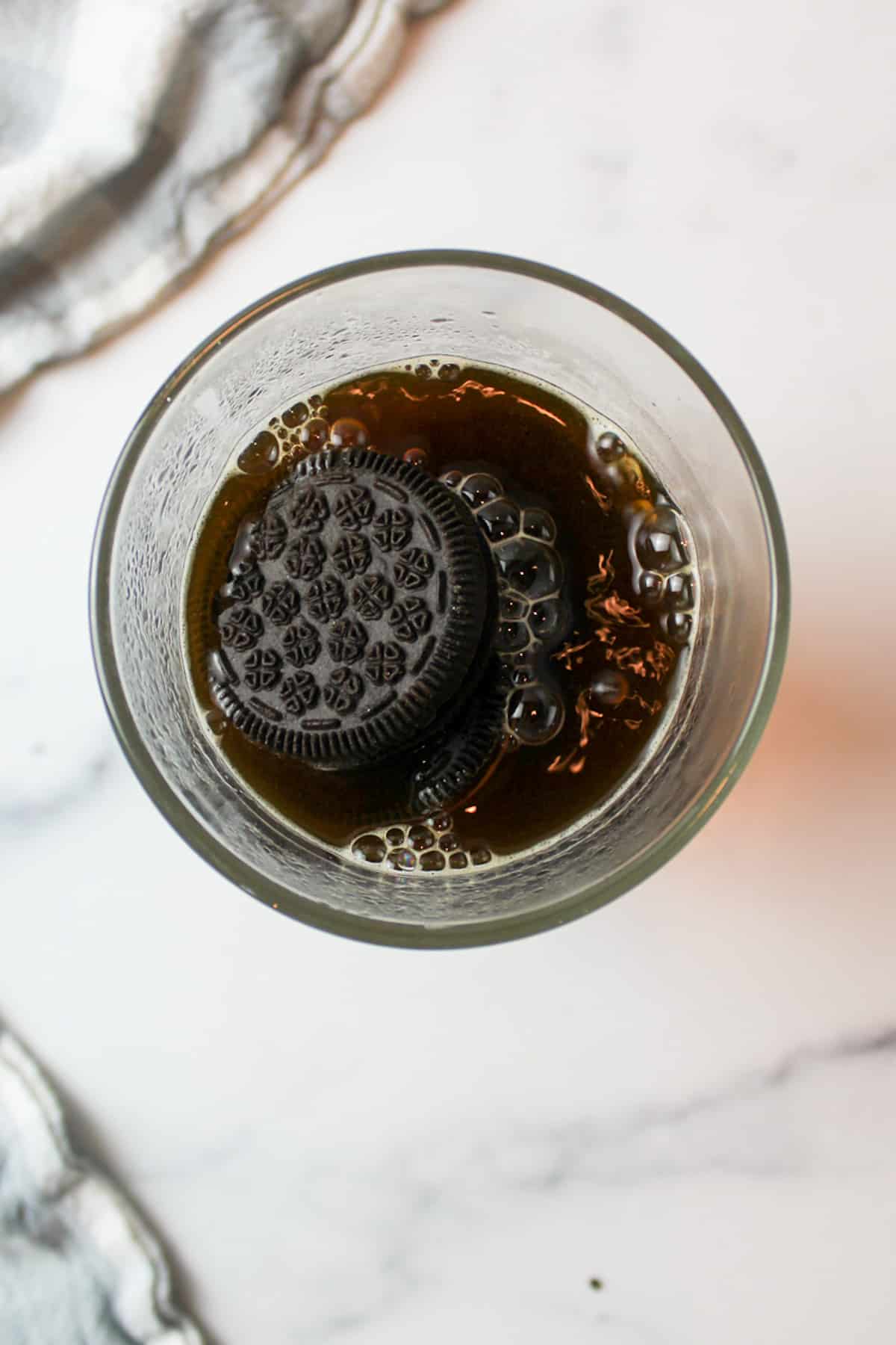 aerial view of glass cup filled with hot coffee and oreo cookeis