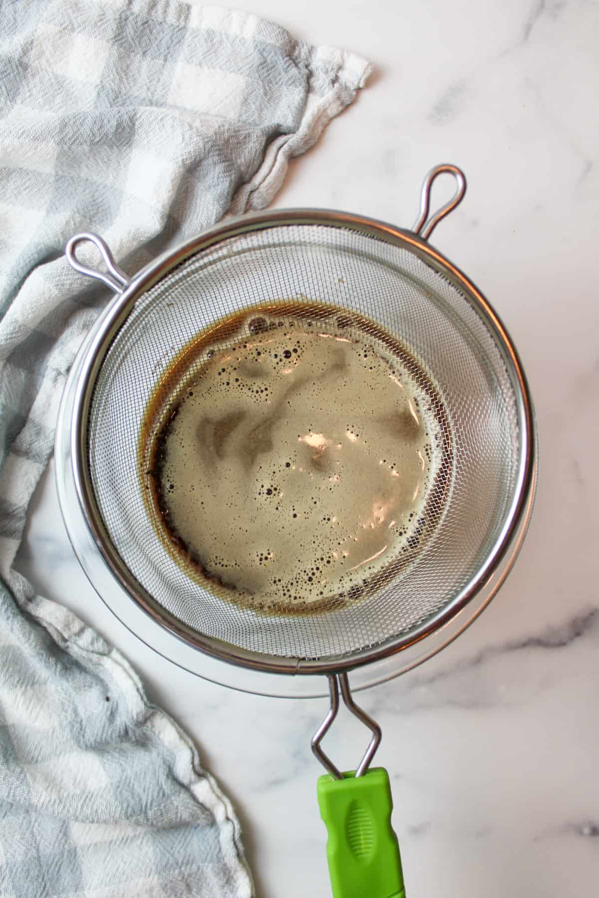 oreo cookie coffee running through a sieve over a bowl.