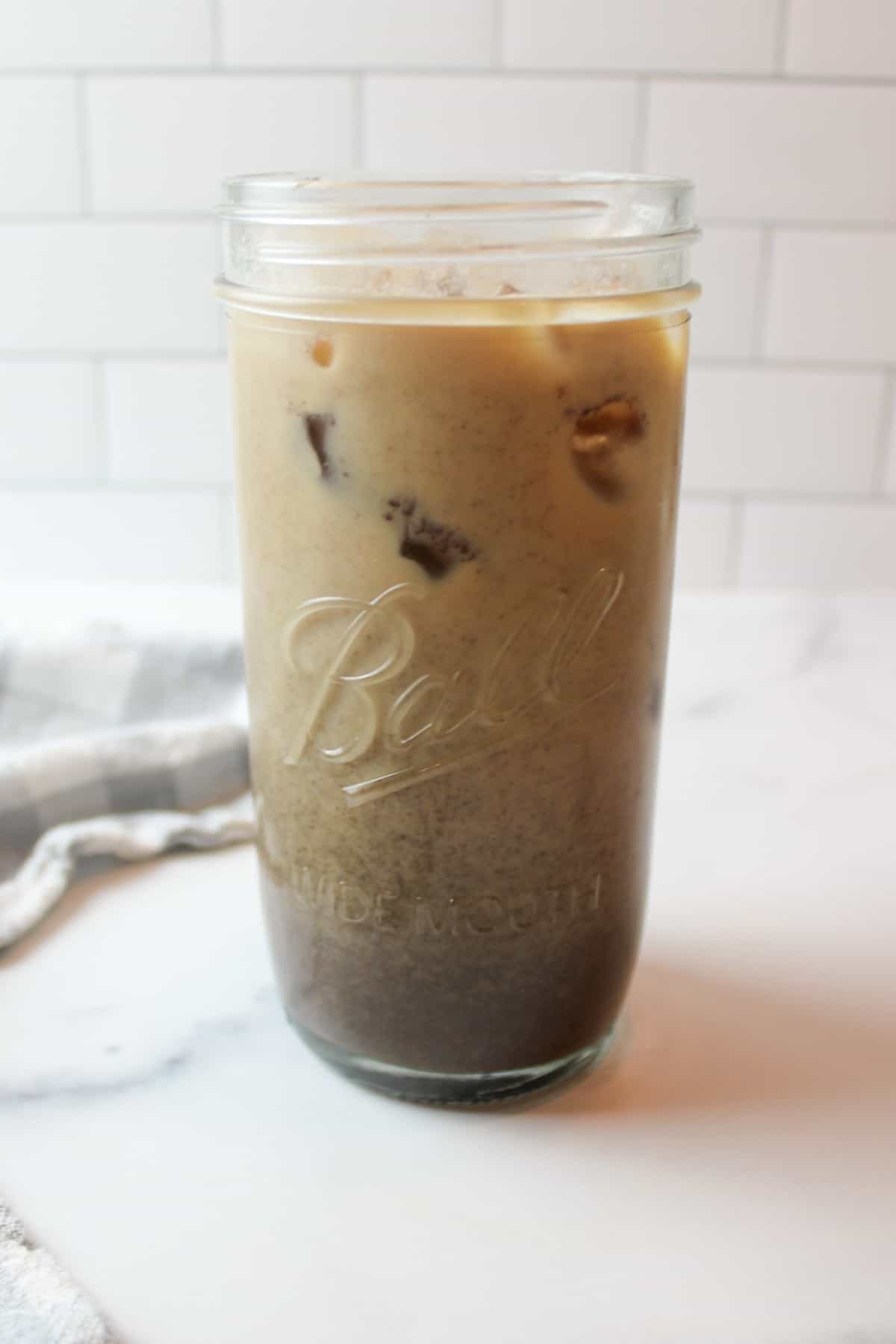 stirred oreo iced coffee in a tall glass cup.