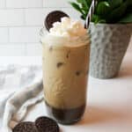 a tall cup of oreo iced coffee topped with whippped cream and a cookie