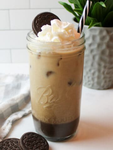 a tall cup of oreo iced coffee topped with whippped cream and a cookie