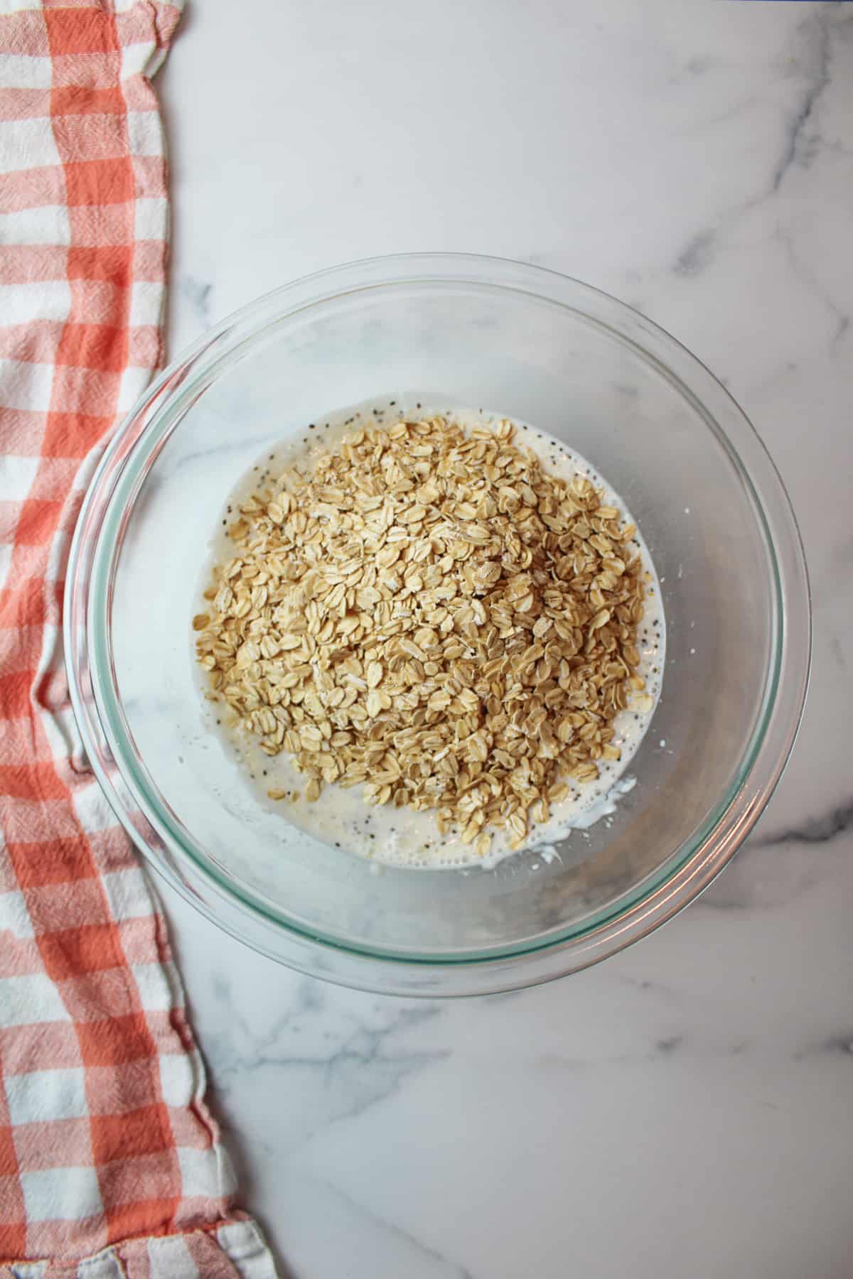 oats on top of milky yogurt mixture in a mixing bowl.