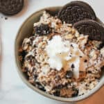 a close up of a bowl filled with oreo overnight oats and topped with whipped cream and oreo cookies