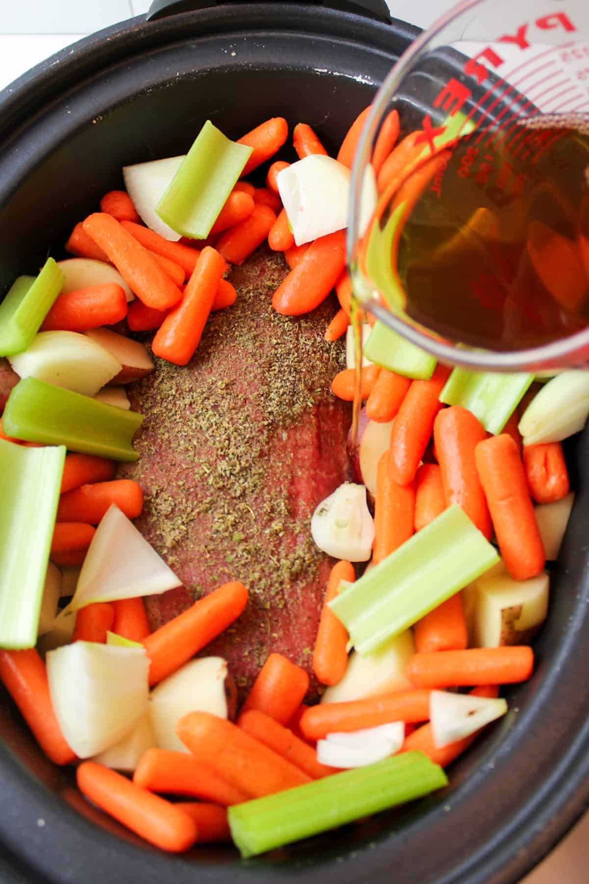 pouring beef broth into the crockpot