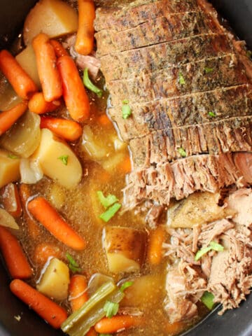 an upclsoe aerial view of cooked beef roast and veggies in slow cooker
