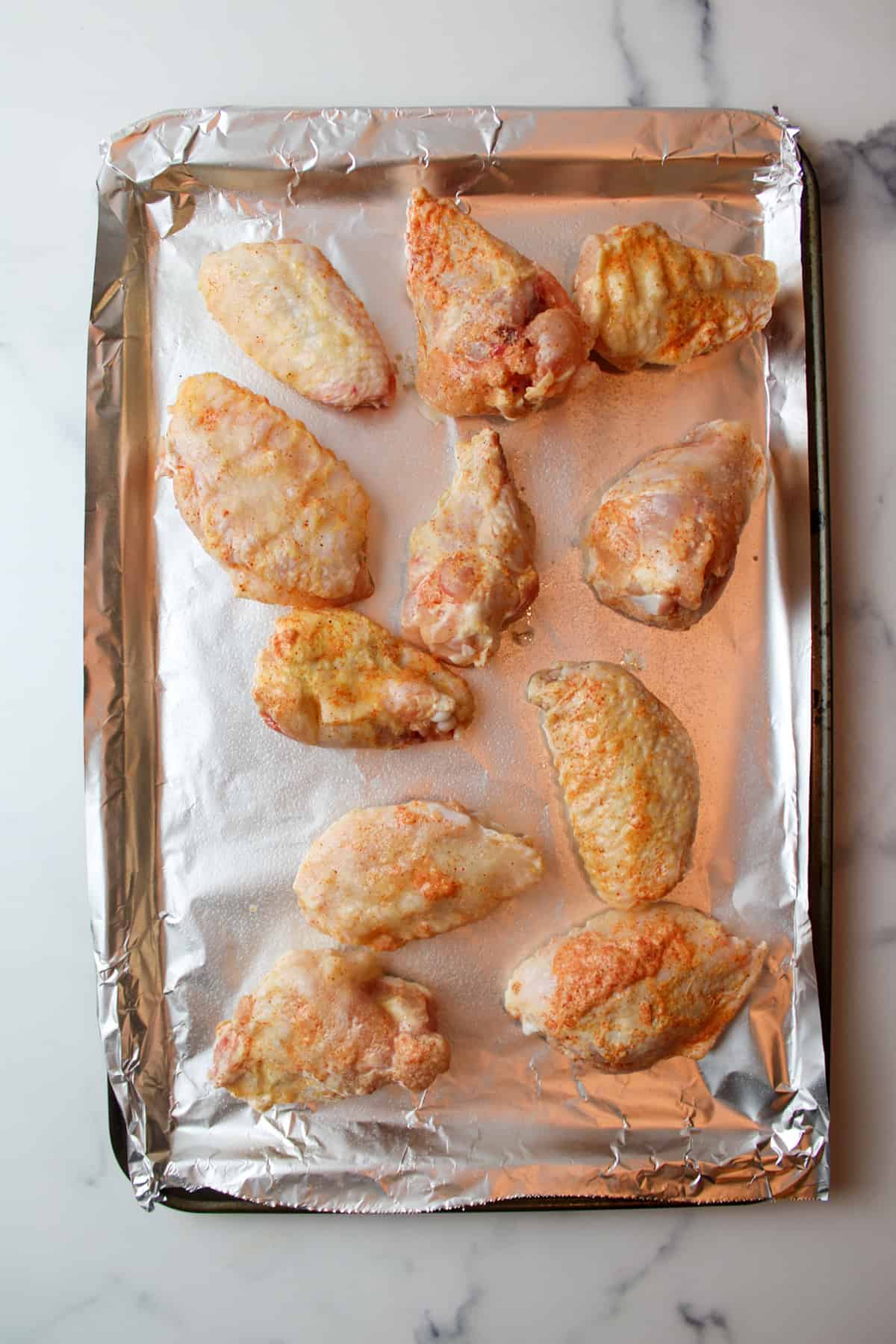 seasoned chicken wings on a foil lined baking sheet.