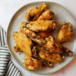 a close up view of a plate filled with soy galic chicken wings