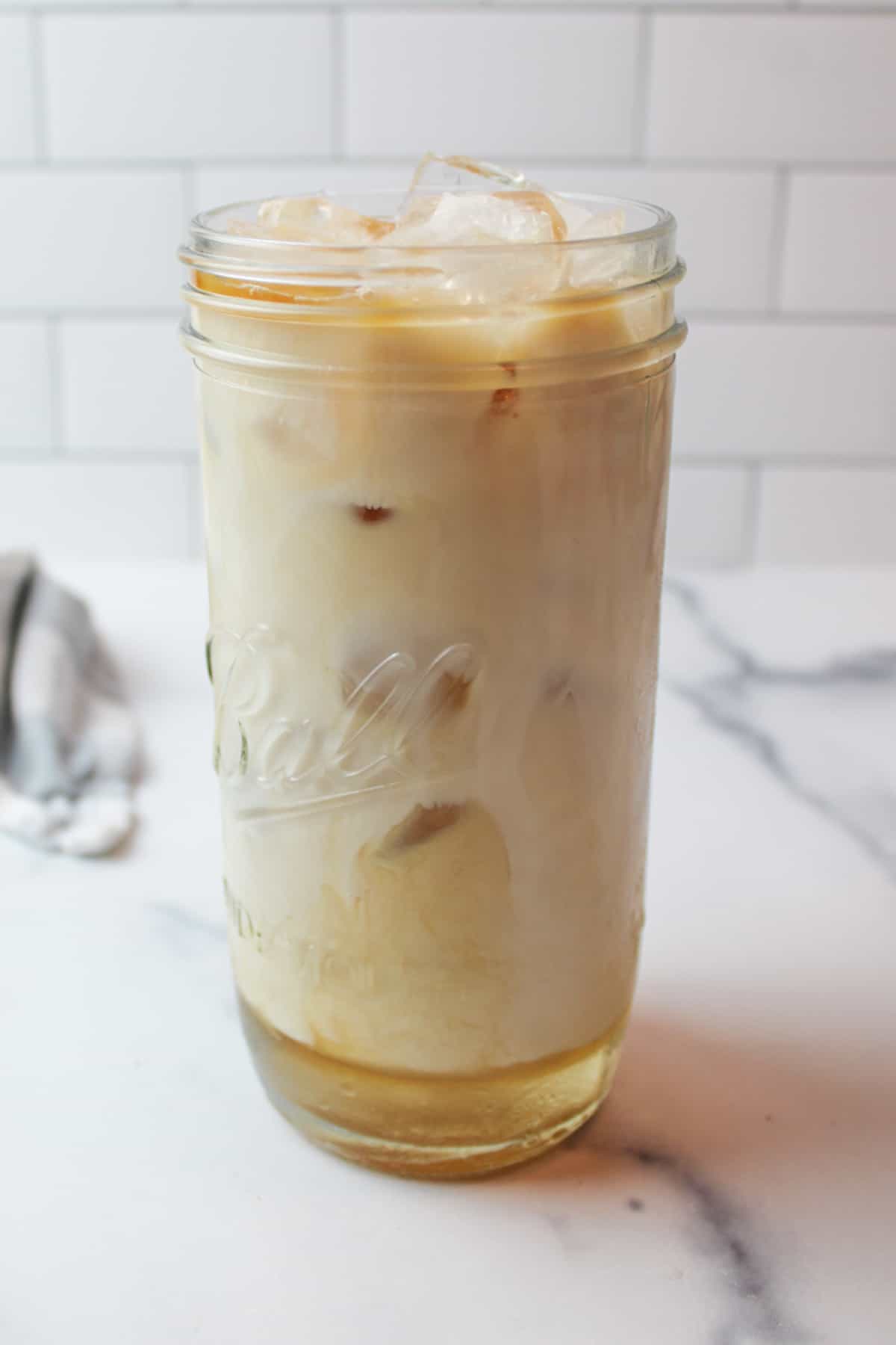 vanilla iced latte ingredients in a tall lass cup unmixed.