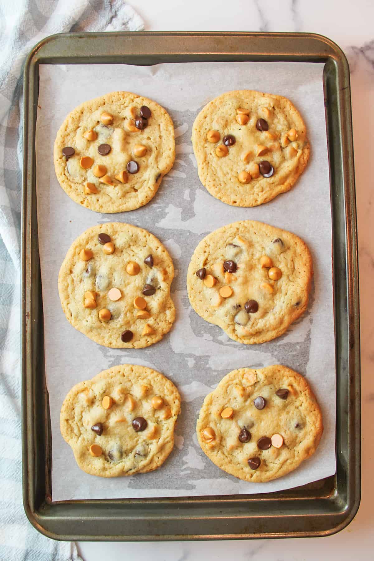 baked butterscotch chocolate chip cookies on a parchment paper lined baking sheet