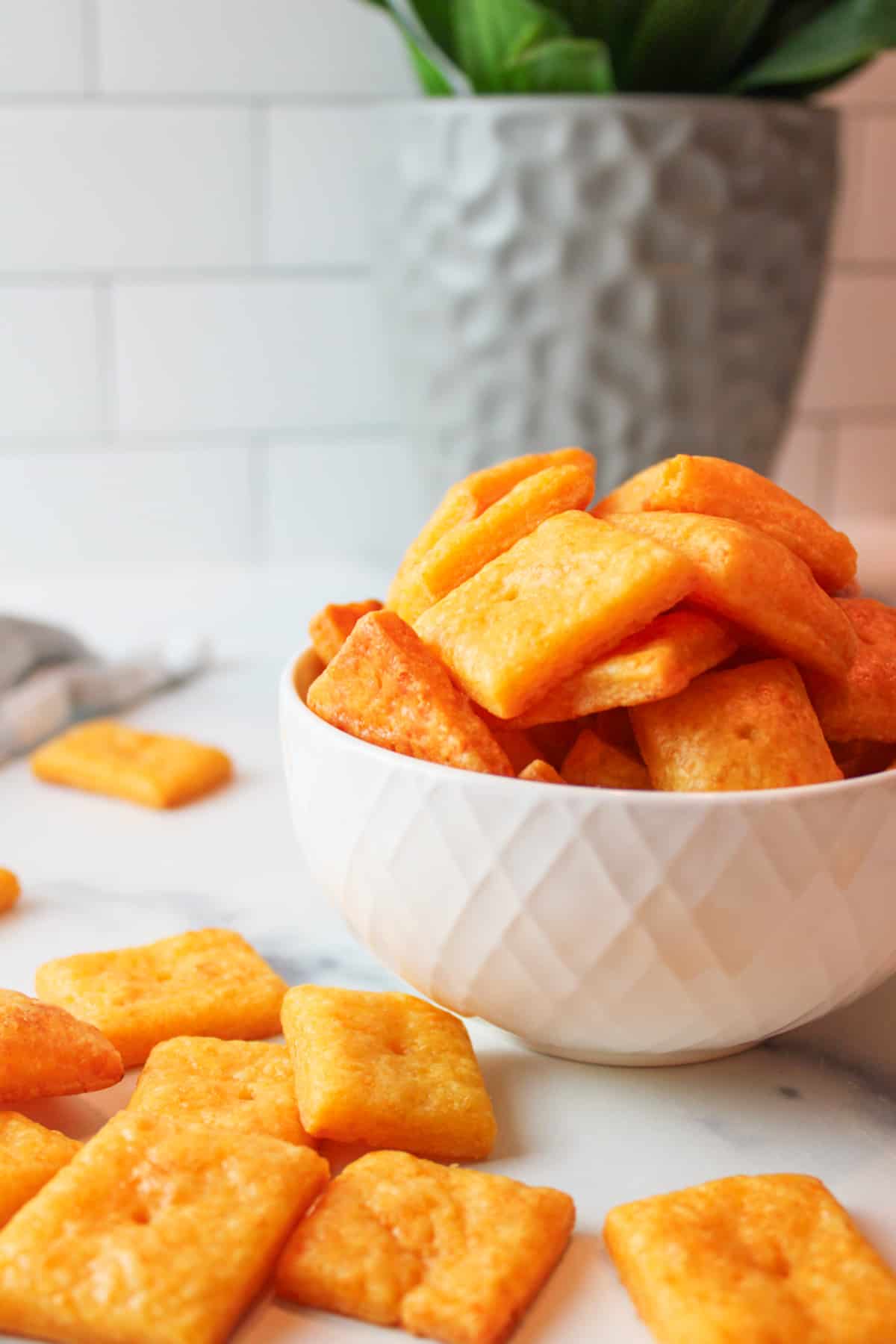 a bowl filled with cheese crackers and some crackers scattered around it.