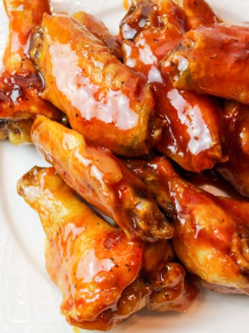 an upclose view of honey gold chicken wings on a white plate
