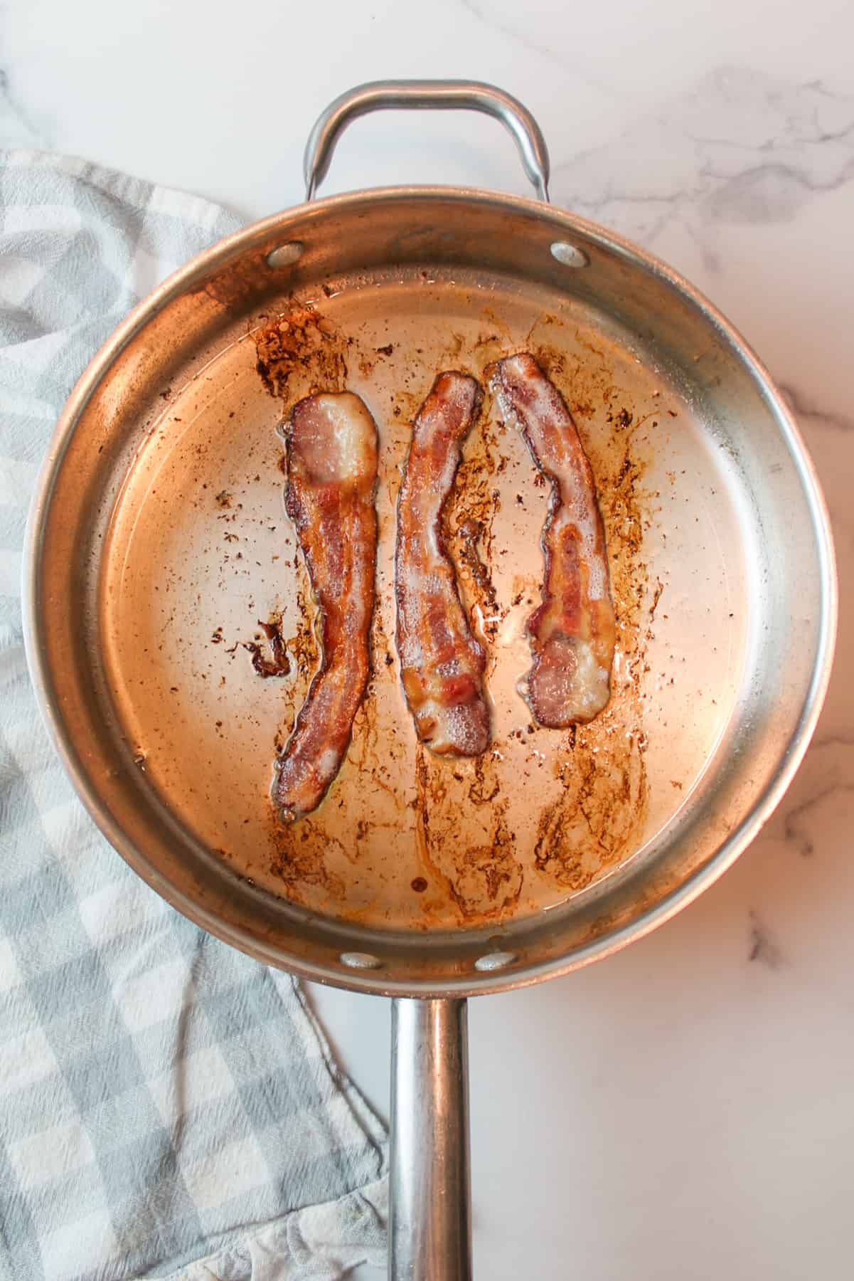 three strips of cooked bacon in a skillet.