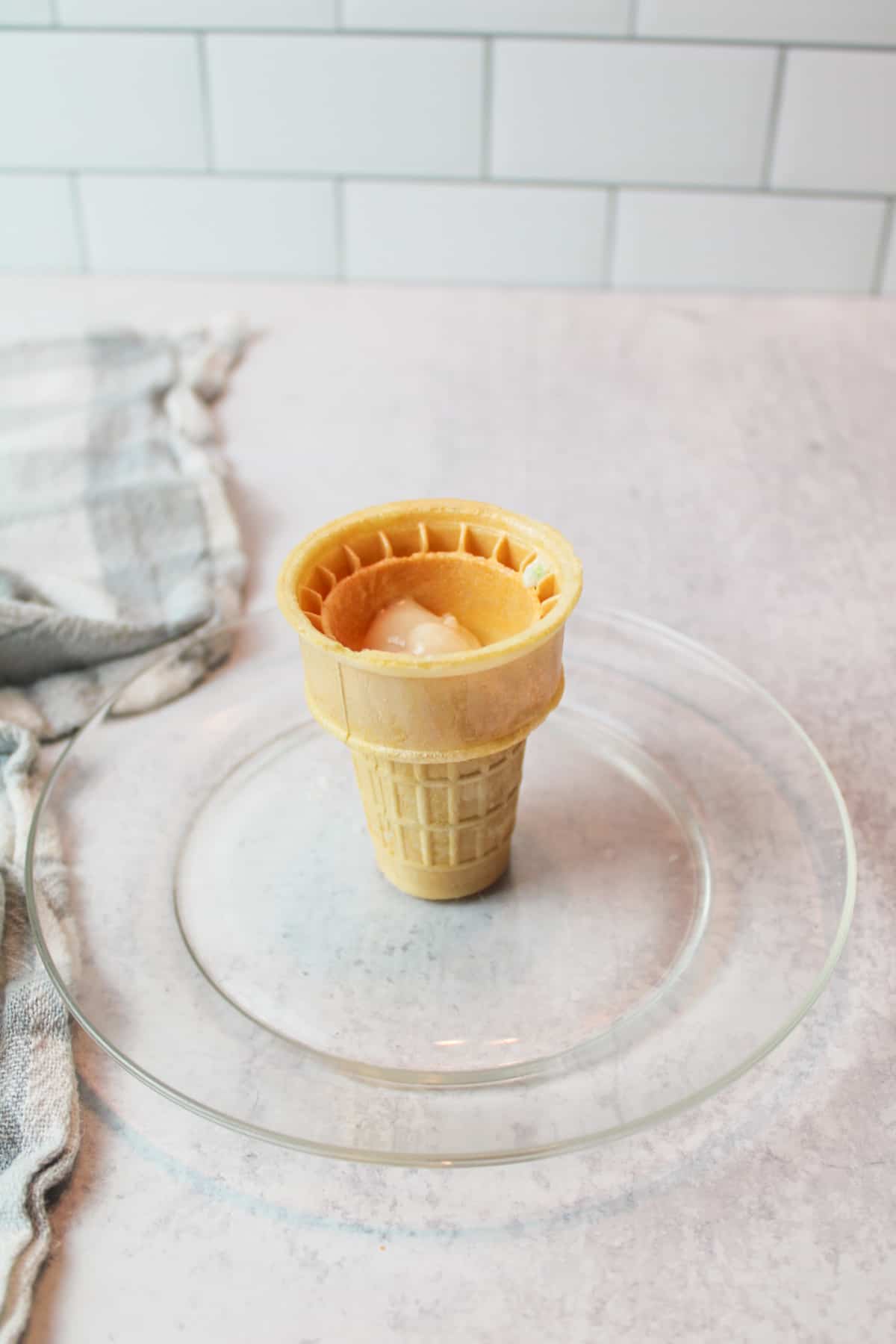 raw cake batter in an ice cream cone on a small plate.