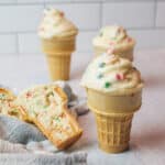 frosted ice cream cone cupcakes with one split open to reveal cake inside.