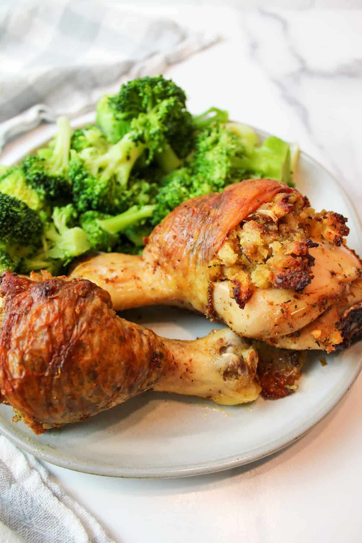 stuffed chicken legs on a plate with steamed broccoli.