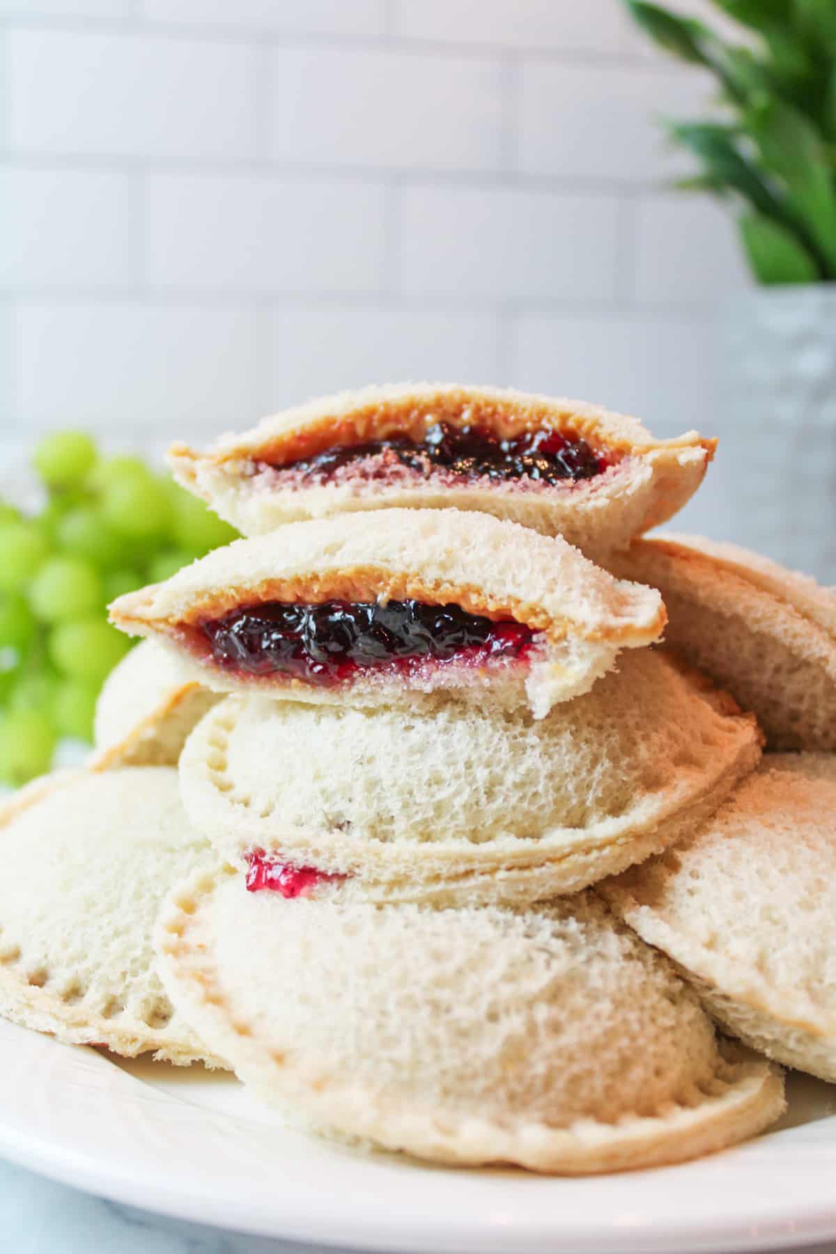 side view of a plate stacked with peanut butter jelly uncrustable sandwiches