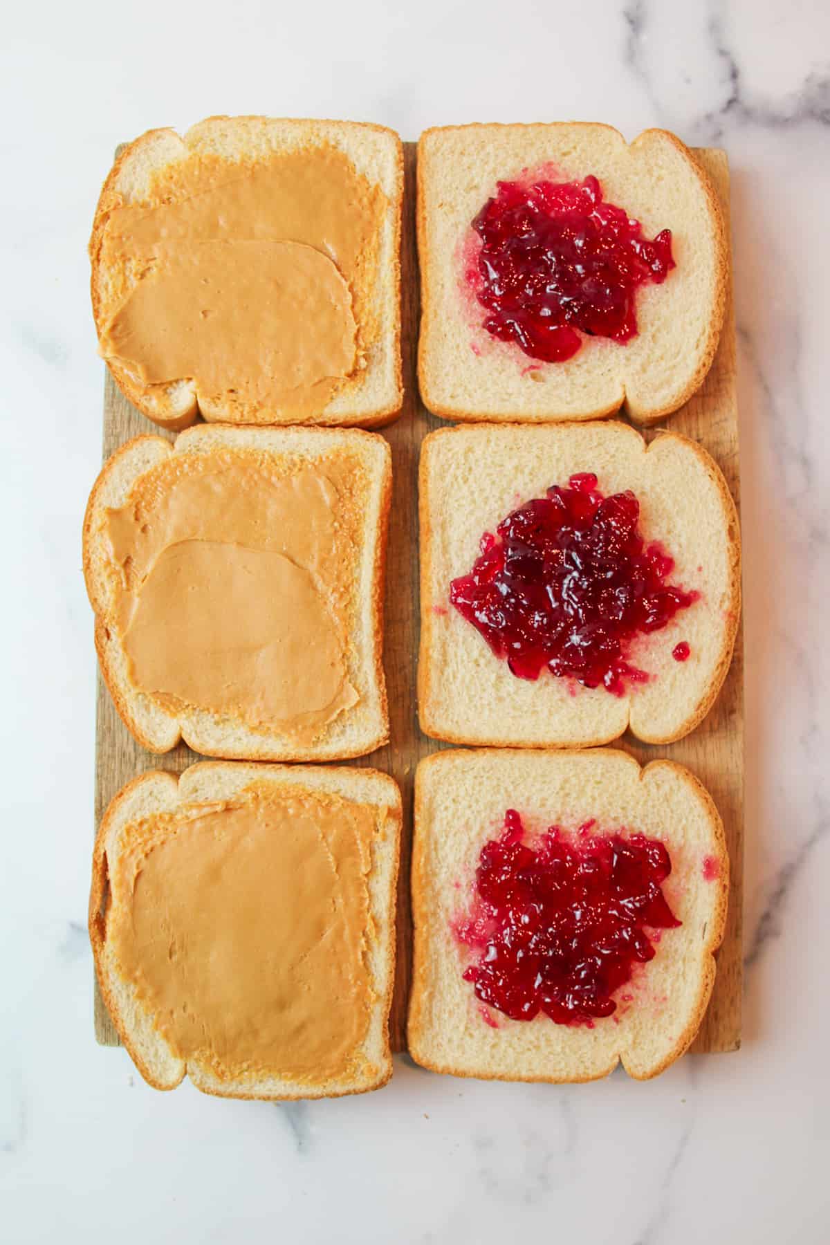 6 slices of white sandwich bread topped with peanut butter and jelly