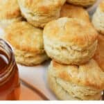 a pile of golden stacked biscuits with a jar of honey.
