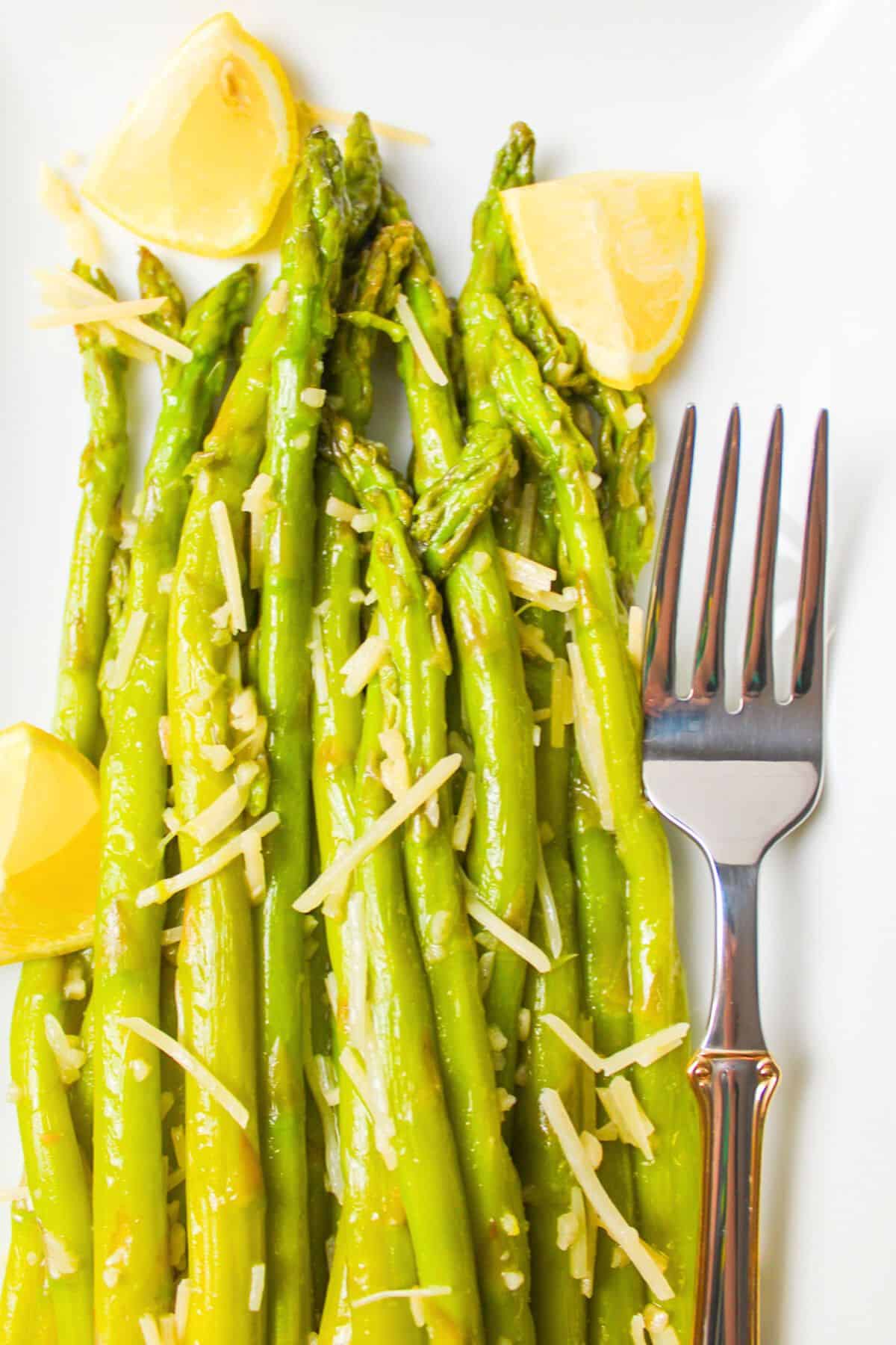 rows of cheese topped asparagus next to a fork.
