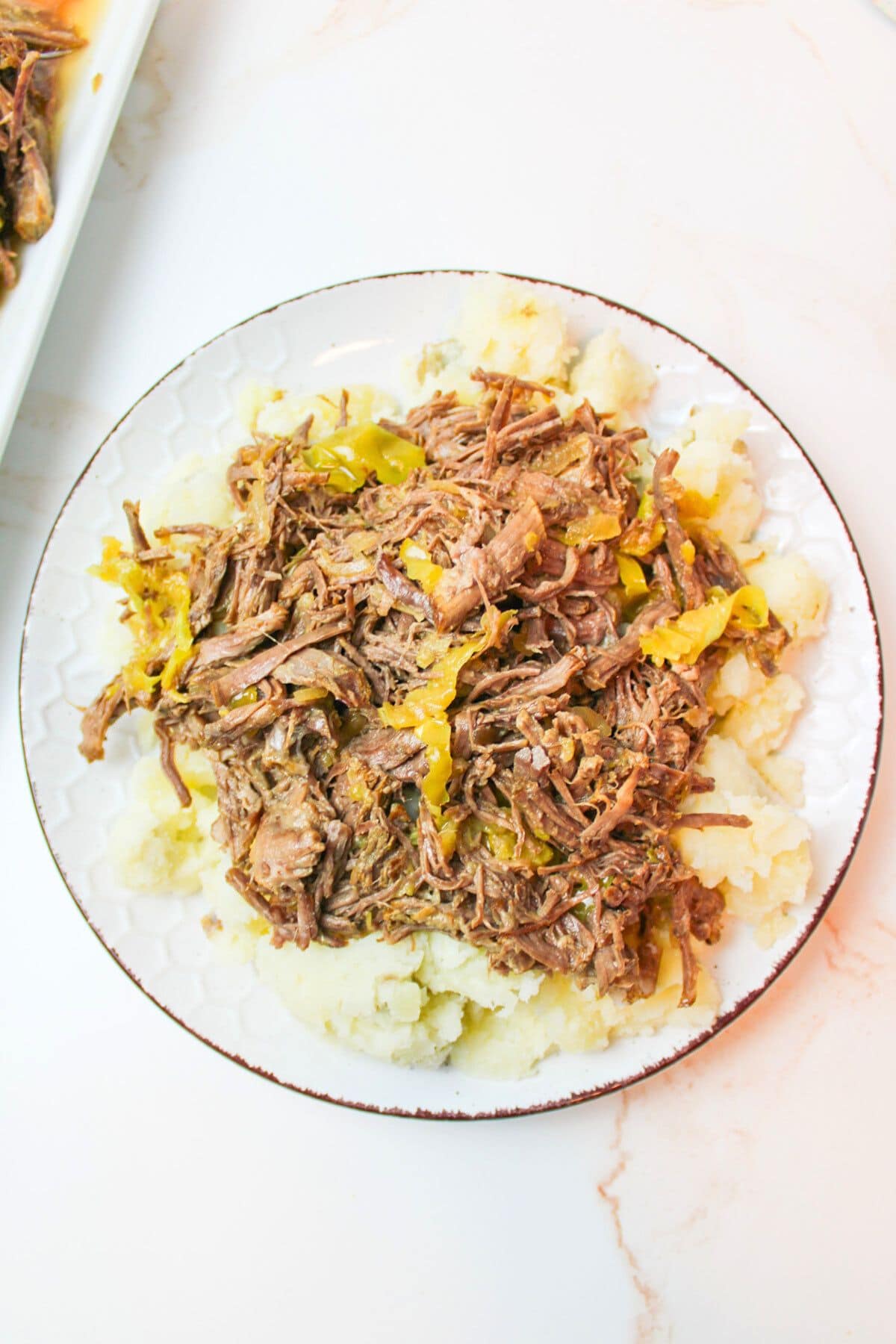 a plate with mashed potatoes and mississippi roast on top.