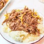 a plate topped with mashed potatoes and shredded mississippi roast.