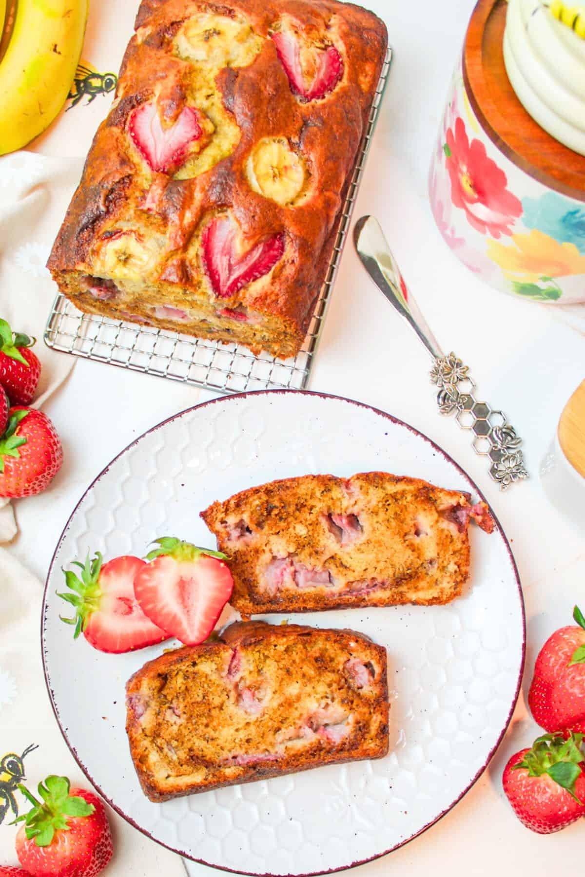 sliced strawberry banana bread both on and off of a serving plate.