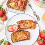 sliced strawberry banana bread on a plate with fresh berries to the side.