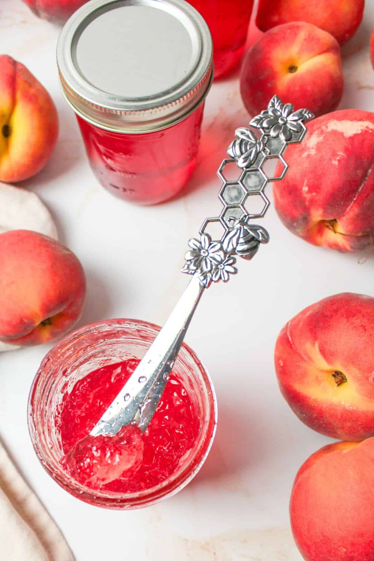 a knife resting in a jar of peach jelly.