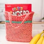 crochet market bag filled with box of cereal citting on counter.