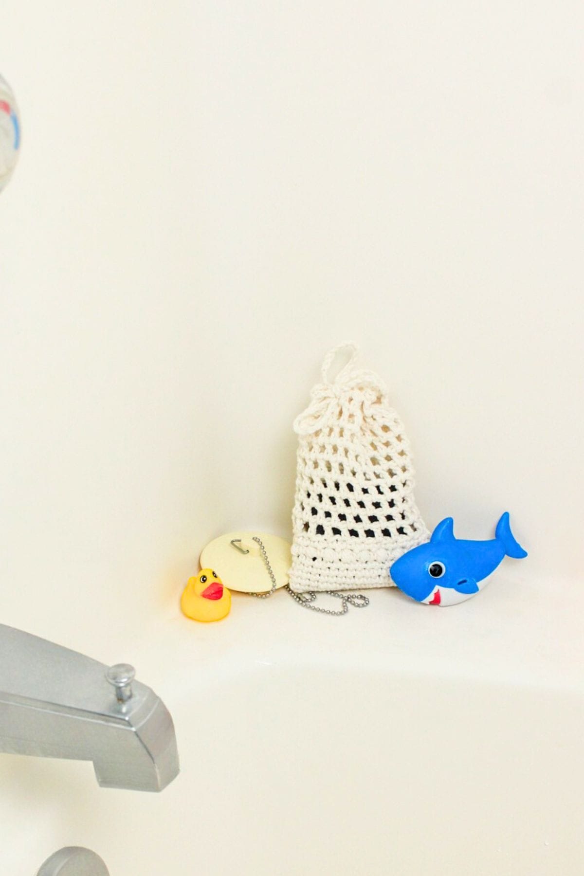 crochet soap saver next to bath tub drain plug and toys.
