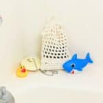 crochet soap saver in bath tub next to drain plug and toys.