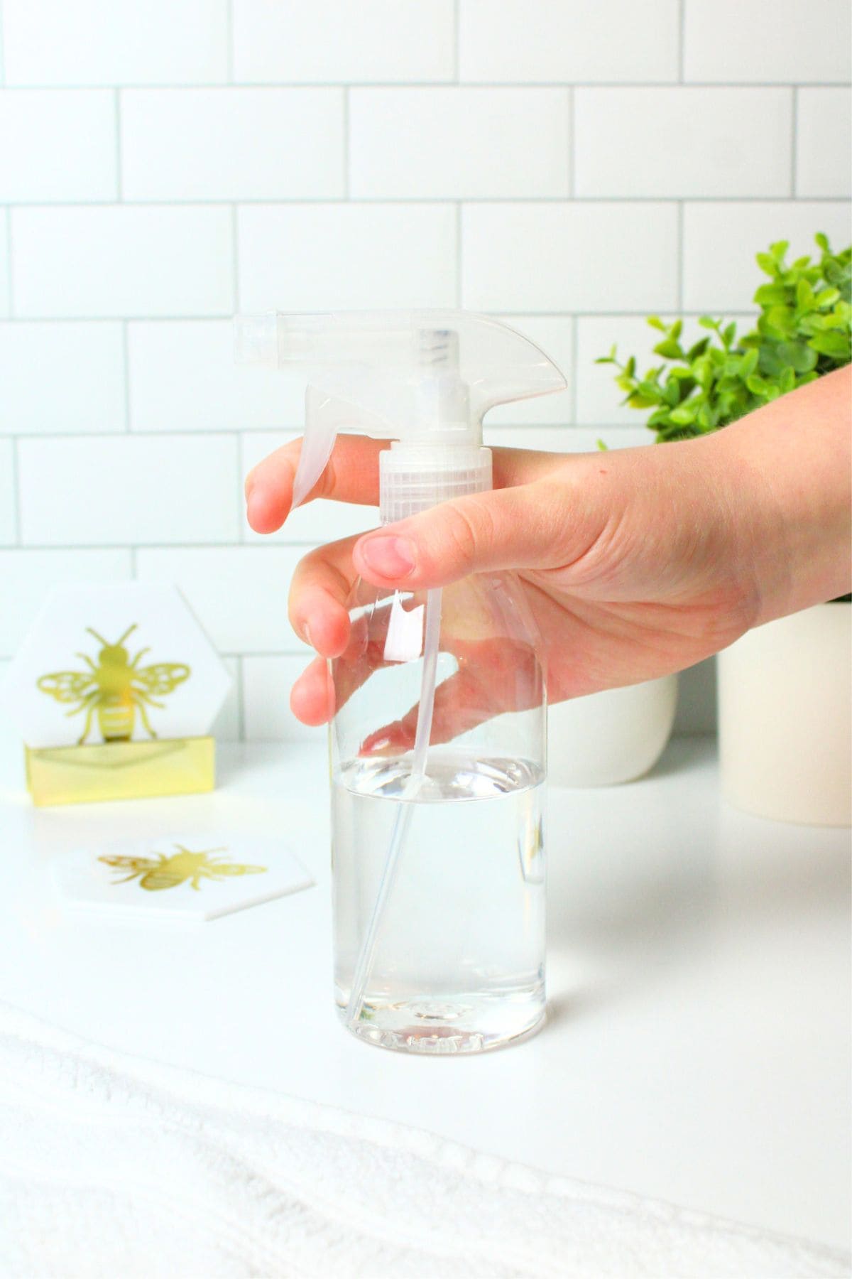 a hand holding the trigger on a clear bottle of disifectant.