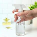 a hand holding a bottle of disinfectant.