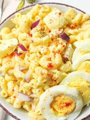 egg pasta salad in a bowl with sliced egg and paprika on top.