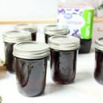 jars of grape jelly in front of bottle of grape juice.