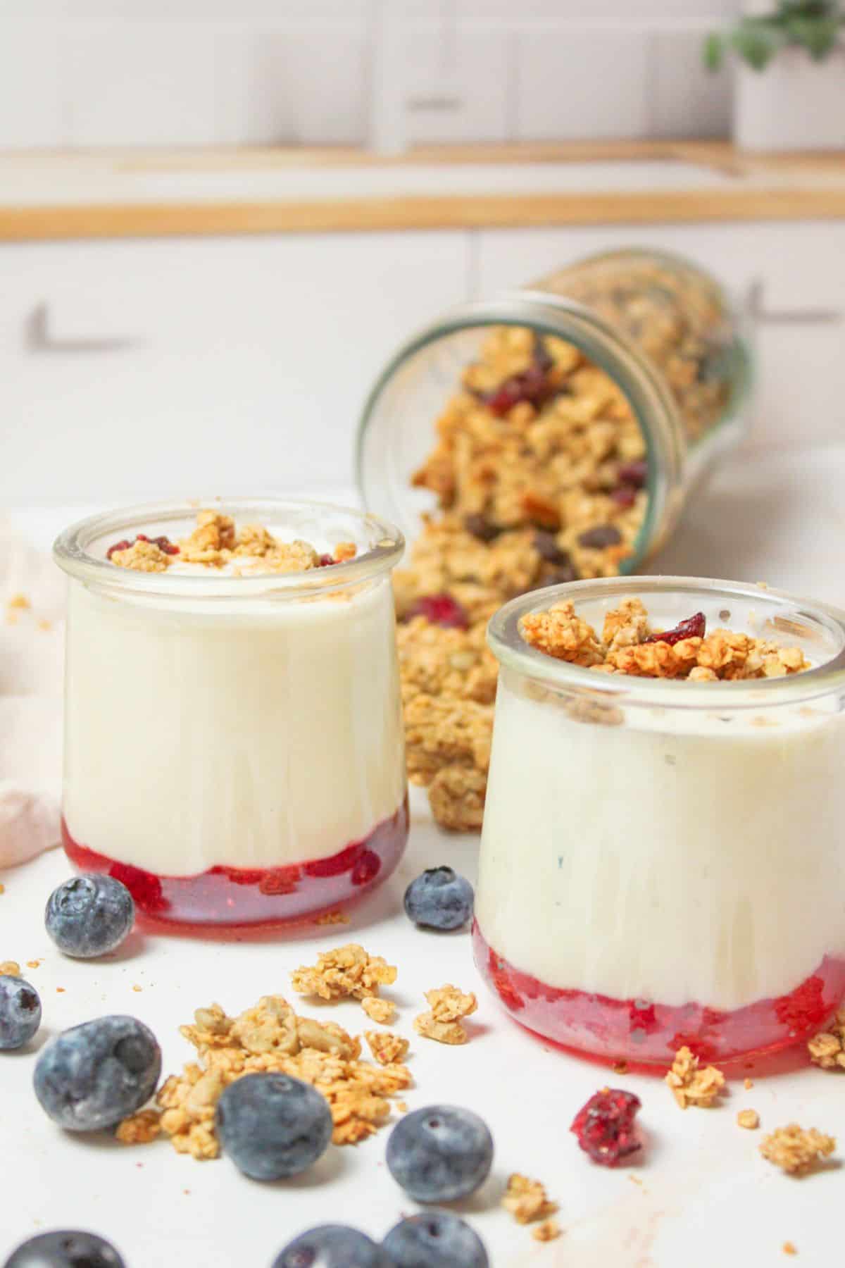 yogurt in cups with jam on bottom and granola on top.
