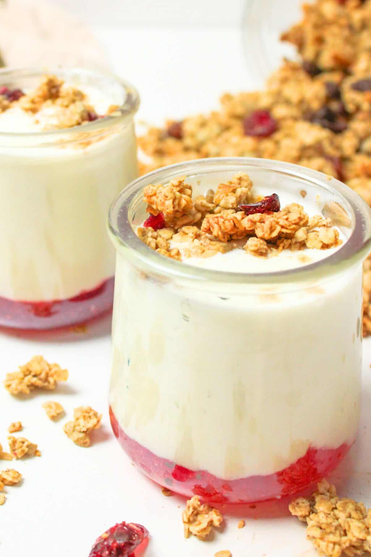 yogurt in cups with jam on bottom and granola on top.