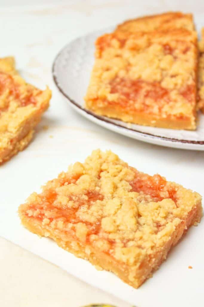jam shortbread bar in front of a plate with more on it.
