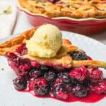 a slice of mixed berry pie topped with vanilla ice cream.