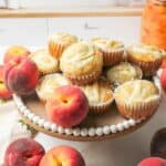 fresh peaches with peaches and cream muffins on a cake plate.