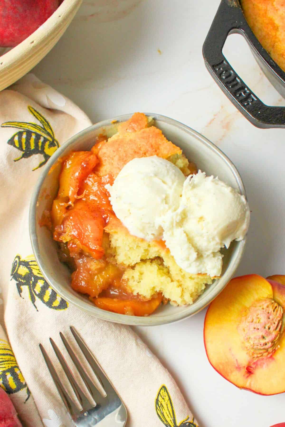 sourdough peach cobbler in a bowl with ice cream.