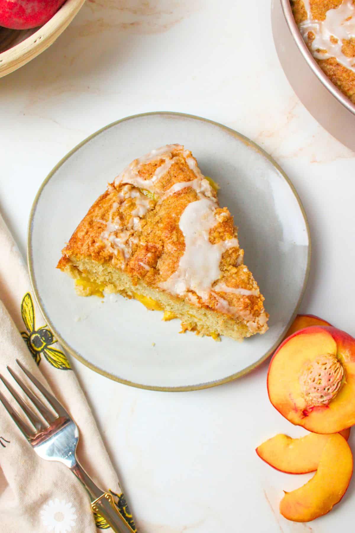 sliced peach coffee cake on a plate topped with icing.