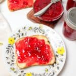 strawberry jam spread over toast on a plate.