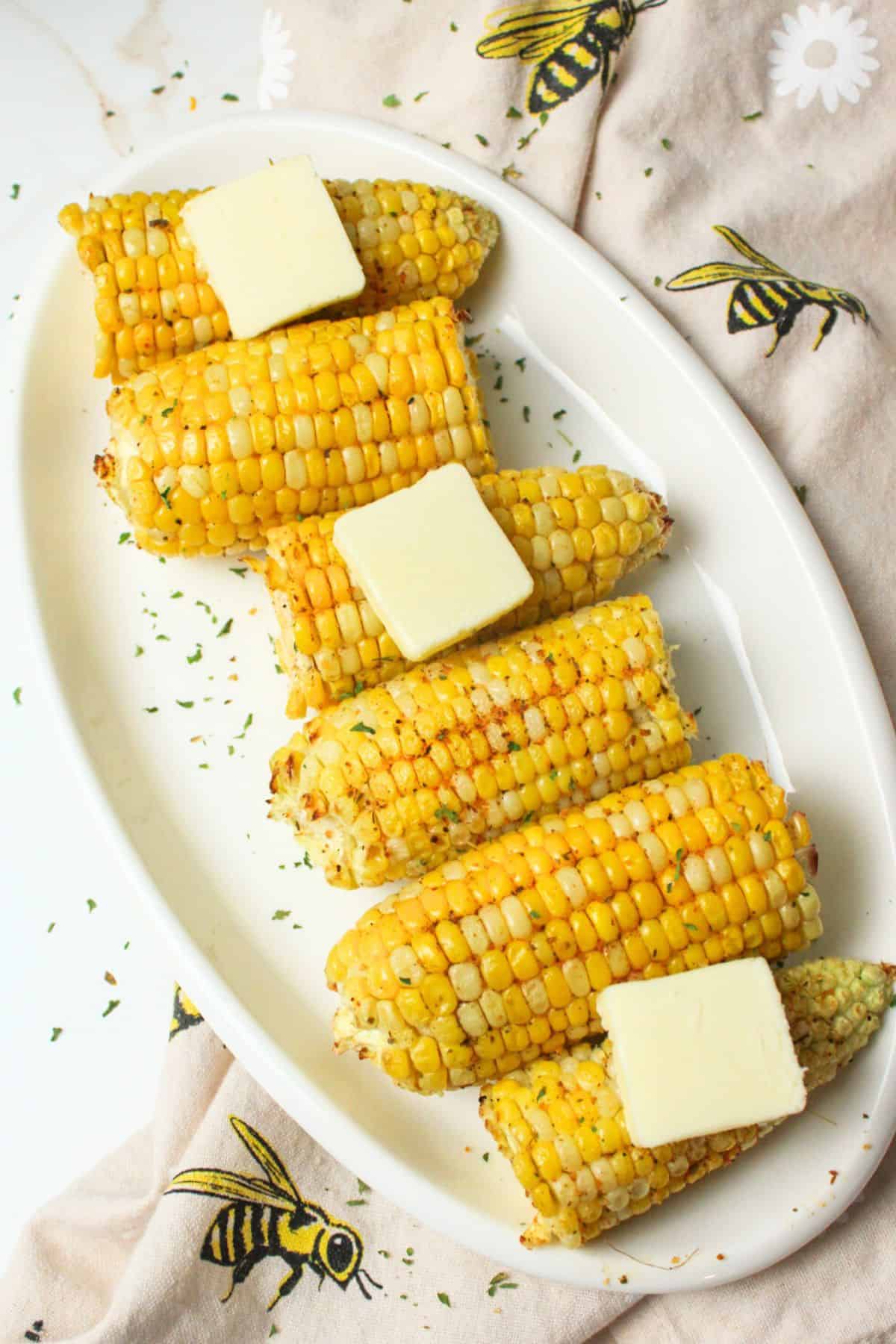 air fried corn cobs on a plate topped with butter.