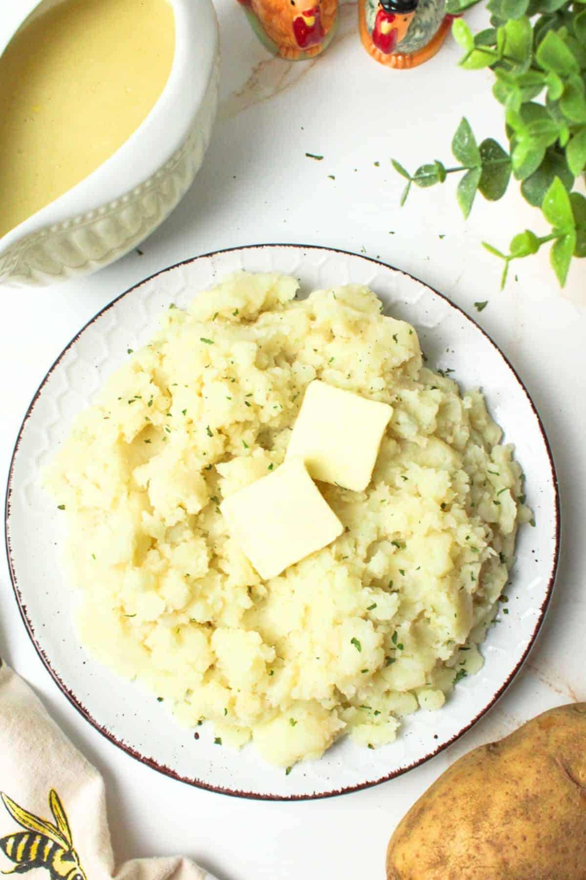mashed potatoes on a plate with butter and parsley.