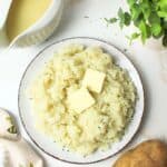 dairy free mashed potatoes on a plate topped with vegan butter.
