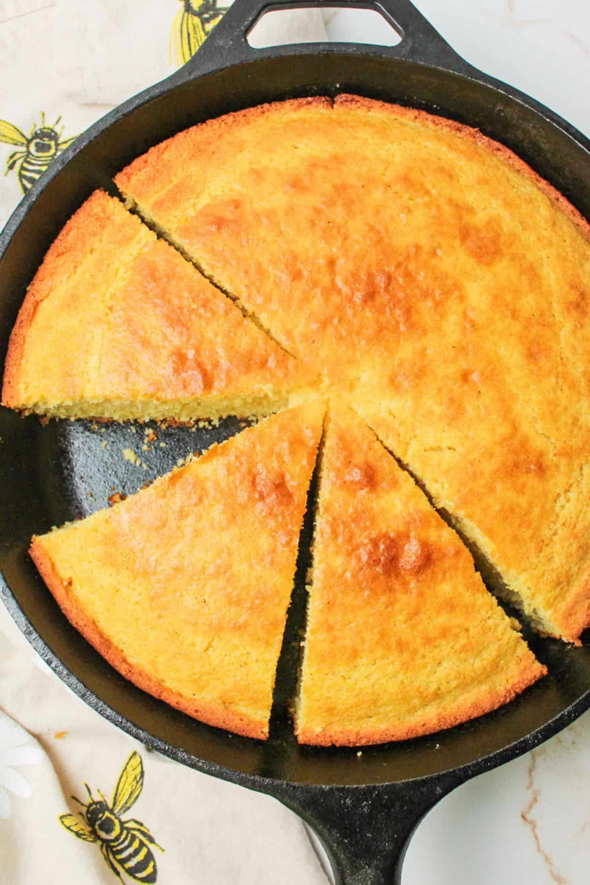 sliced cornbread in a skillet with a slice missing.