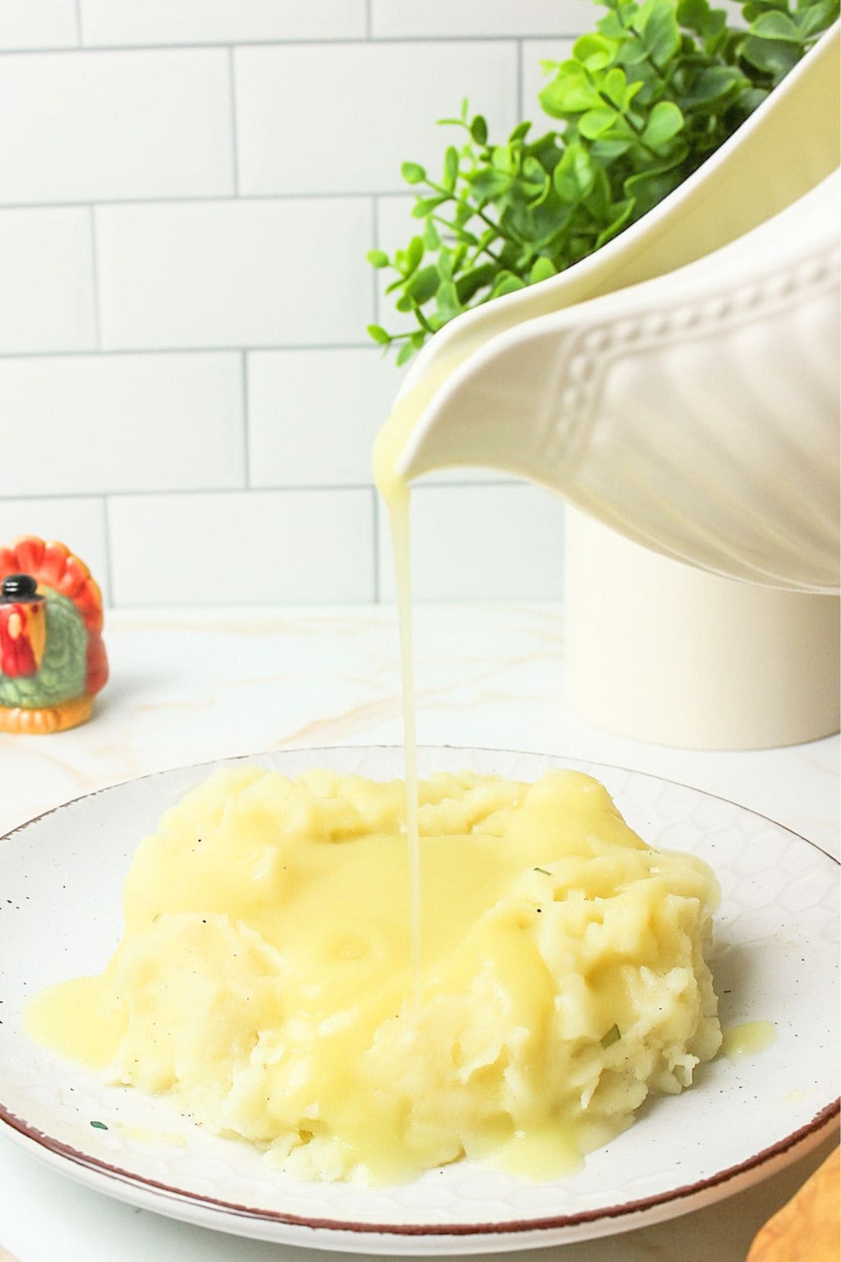 pouring sourdough gravy onto mashed potatoes from gravy boat.